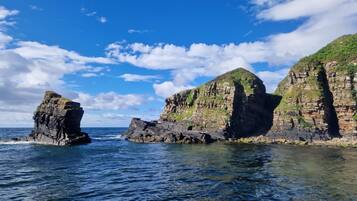 A coastal landscape with rocky cliffs and clear blue water.