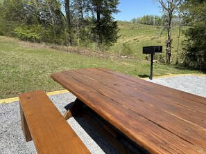 A wooden picnic table with benches in a grassy outdoor area. - Sleeps8 w/ hot tub, pool table/ fire pit, plenty of outdoor seating w/ big yard (Sevierville)