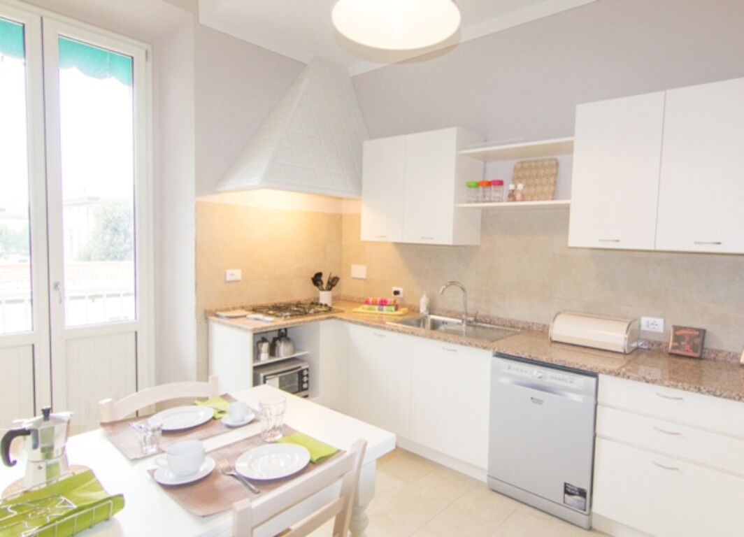 A compact kitchen with white cabinets, a dishwasher, and a dining area with a table set for four.