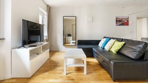 A modern living room with a flat-screen TV, white coffee table, and a black leather sofa with colorful cushions. - CDT Duomo - Three Bedroom Apartment, Sleeps 6 (Firenze)