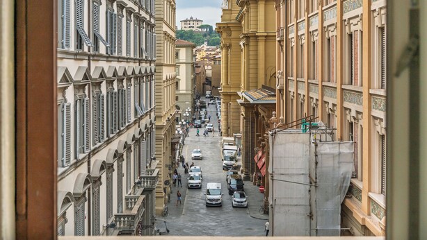 A narrow street with buildings on both sides, cars parked along the street, and a few pedestrians. - CDT Duomo - Three Bedroom Apartment, Sleeps 6 (Firenze)