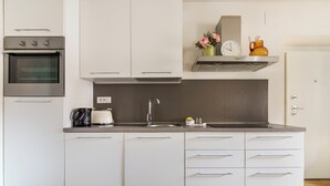 A modern kitchen with white cabinets, a stainless steel oven, a sink, and a countertop with a kettle and a clock. - CDT Duomo - Three Bedroom Apartment, Sleeps 6 (Firenze)
