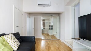 A modern living room with a black leather sofa, a large flat-screen TV, and a wooden floor. - CDT Duomo - Three Bedroom Apartment, Sleeps 6 (Firenze)