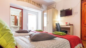 Una habitación de hotel con dos camas, un escritorio con una silla, un televisor y un espejo.