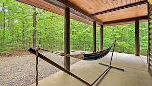 Una hamaca bajo una pérgola de madera con vista al bosque.
