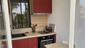 Une cuisine compacte équipée d’un évier, d’une cuisinière et d’un coin repas avec une table et une chaise.