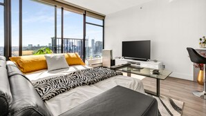 Un dormitorio moderno con una cama grande, televisión y vistas a la ciudad.