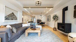 A modern living room with a sofa, coffee table, fireplace, and a dining area in the background. - Tremblant Prestige - Verbier 14-102 (Mont-Tremblant)