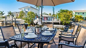 A dining table set outdoors with a view of a canal and buildings in the background.