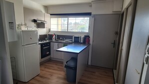 Una cuina compacta amb nevera, fogó, microones i rentamics.