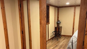 A room with wooden paneling, a bed with patterned bedding, a chair, and a lamp. - Country side retreat, perfect place for family fun and hunting. (Marshall)