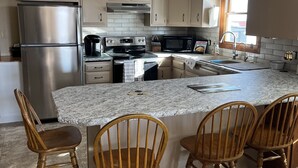 A modern kitchen with a large island, stainless steel appliances, and wooden chairs. - Country side retreat, perfect place for family fun and hunting. (Marshall)