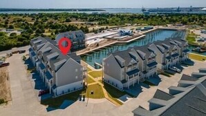 Een modern hotel met een centraal gelegen zwembad, omgeven door gastenkamers en een aangelegde tuin.