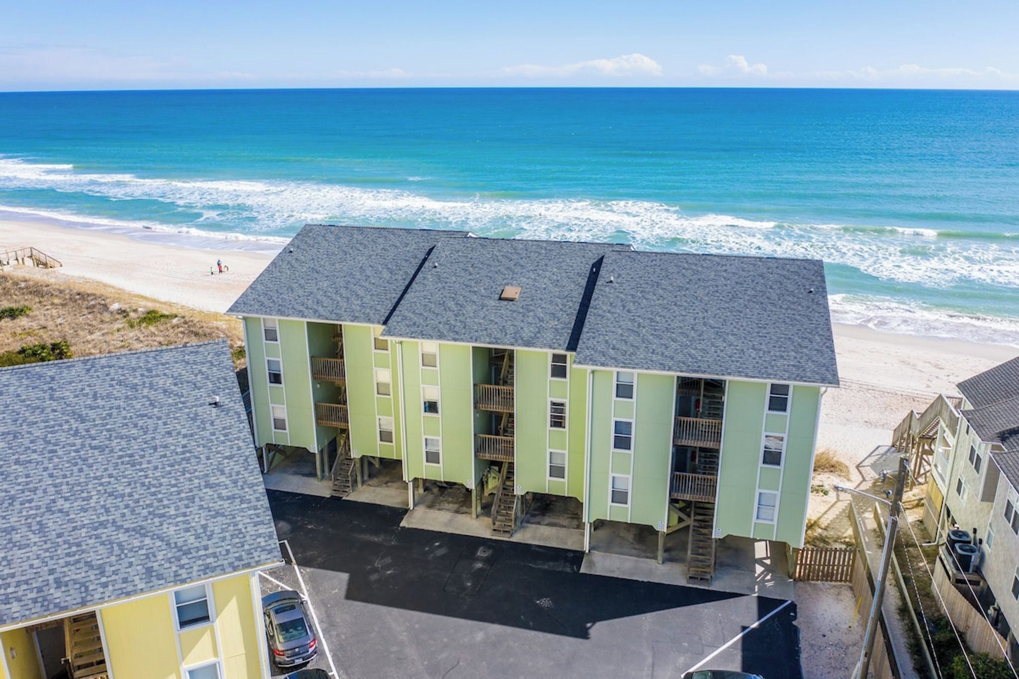 A multi-story building with a flat roof, located near a beach with ocean views.