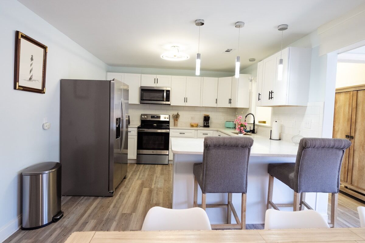 A modern kitchen with white cabinets, stainless steel appliances, and a central island with bar stools.