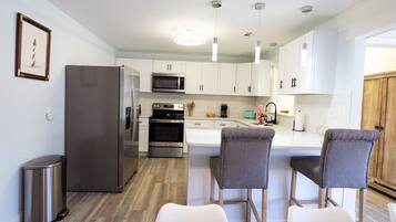 A modern kitchen with white cabinets, stainless steel appliances, and a central island with bar stools.