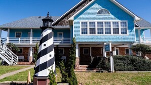 Une maison à deux étages, avec une façade bleue et un phare devant.