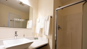 Une salle de bain avec un lavabo blanc, un miroir et une cabine de douche en verre.