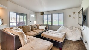 Un salon avec un canapé d’angle, un pouf et un fauteuil en forme de sac.
