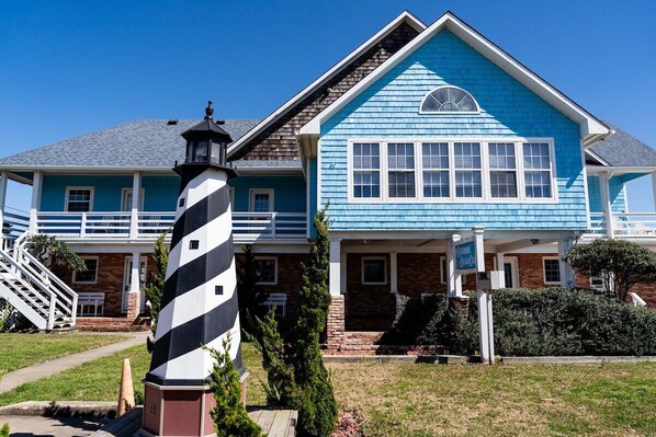 A two-story house with a blue exterior and a lighthouse in front. - Andrew - Offshore Beach Club (Buxton)