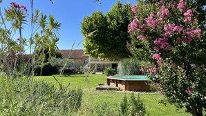 A backyard with a wooden pool, a lawn, and a house in the background.