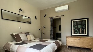 A bedroom with a bed, a dresser, a mirror, and a framed botanical print on the wall.