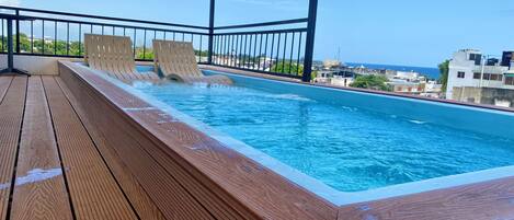 Una piscina al aire libre, sillones reclinables de piscina