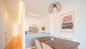 Une cuisine moderne avec des meubles blancs, un îlot central et un luminaire suspendu.