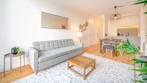 Un salon moderne avec un canapé gris, une table basse en bois et un coin repas comprenant une petite table et des chaises.