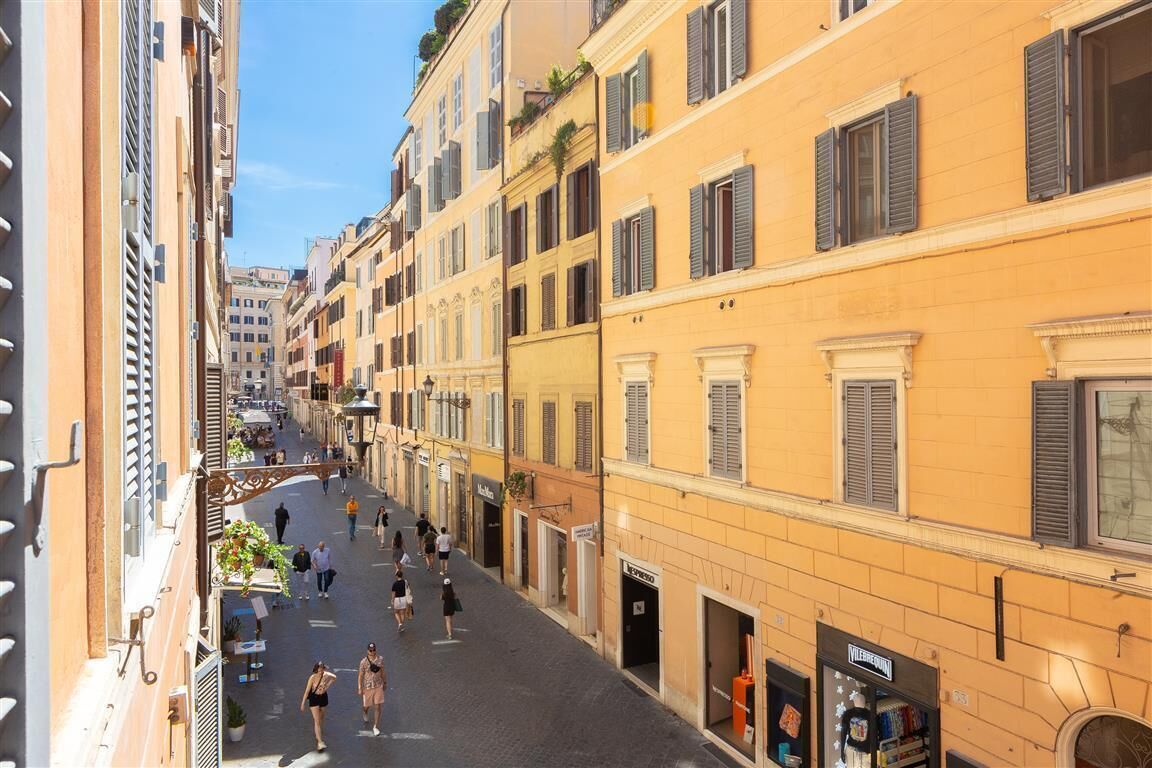 A narrow street lined with yellow buildings, some with shutters, and a few balconies.