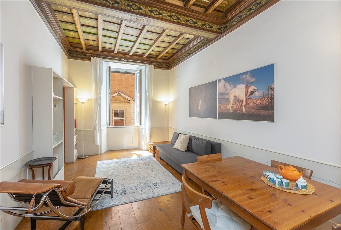 Un accogliente soggiorno con un tavolo da pranzo in legno, un divano e vista su un paesaggio desertico attraverso la porta aperta.