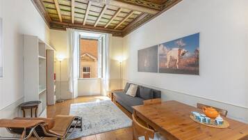 Un accogliente soggiorno con un tavolo da pranzo in legno, un divano e vista su un paesaggio desertico attraverso la porta aperta.
