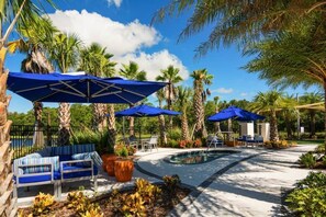 A poolside area with blue umbrellas, lounge chairs, and a small pool.