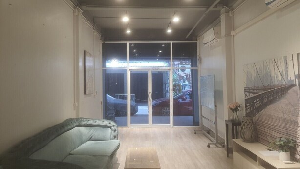 A modern living room with a glass door leading to a street view, a sofa, a small table, and a wall-mounted TV.