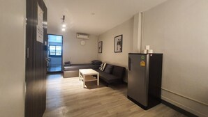 A modern living room with a sofa, a small table, and a refrigerator.