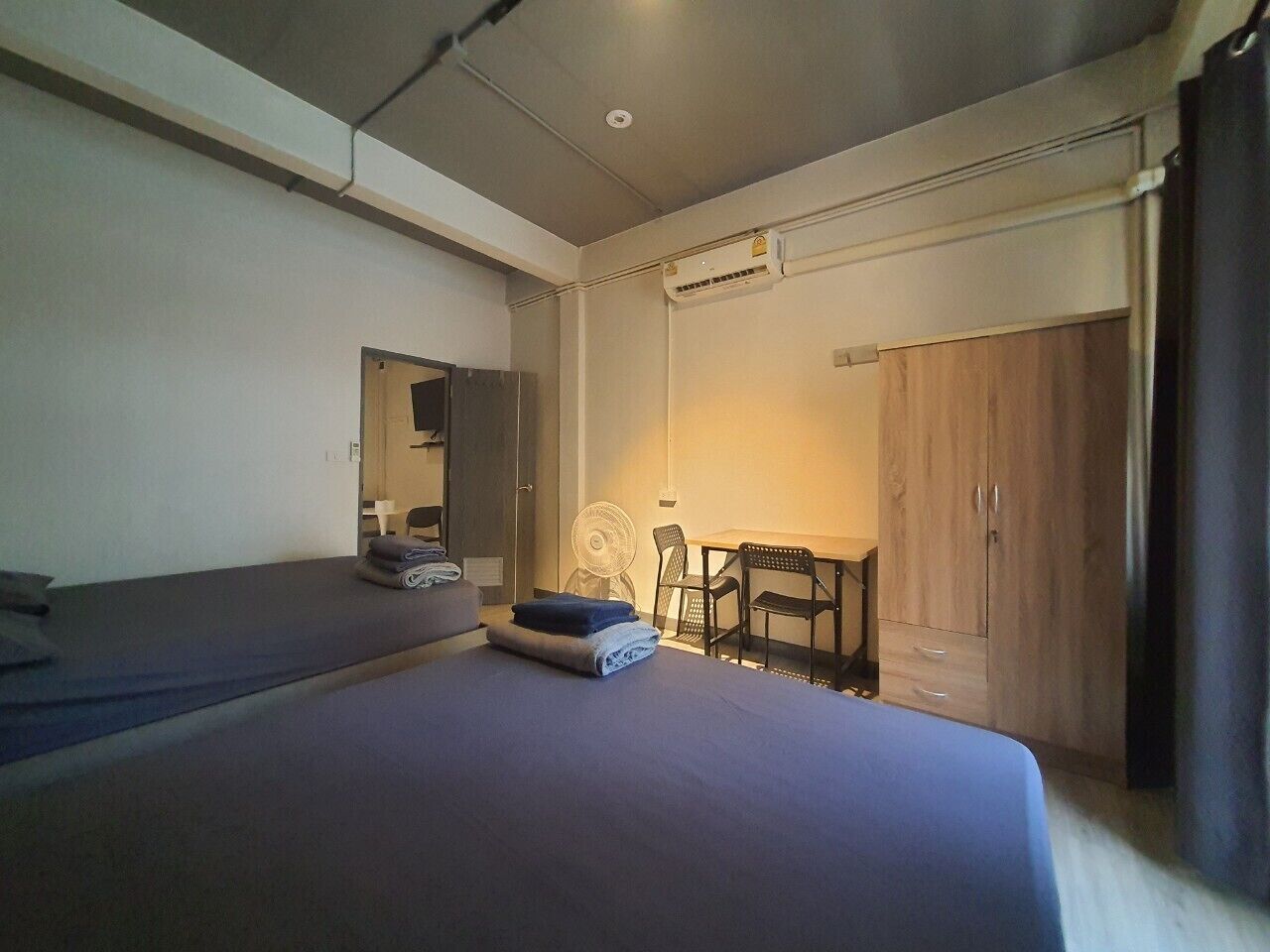 A bedroom with a bed, a desk, a chair, and a wardrobe.