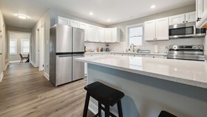 Une cuisine moderne dotée d’appareils électroménagers en acier inoxydable, d’un grand îlot central et d’un coin repas avec une table et des chaises.
