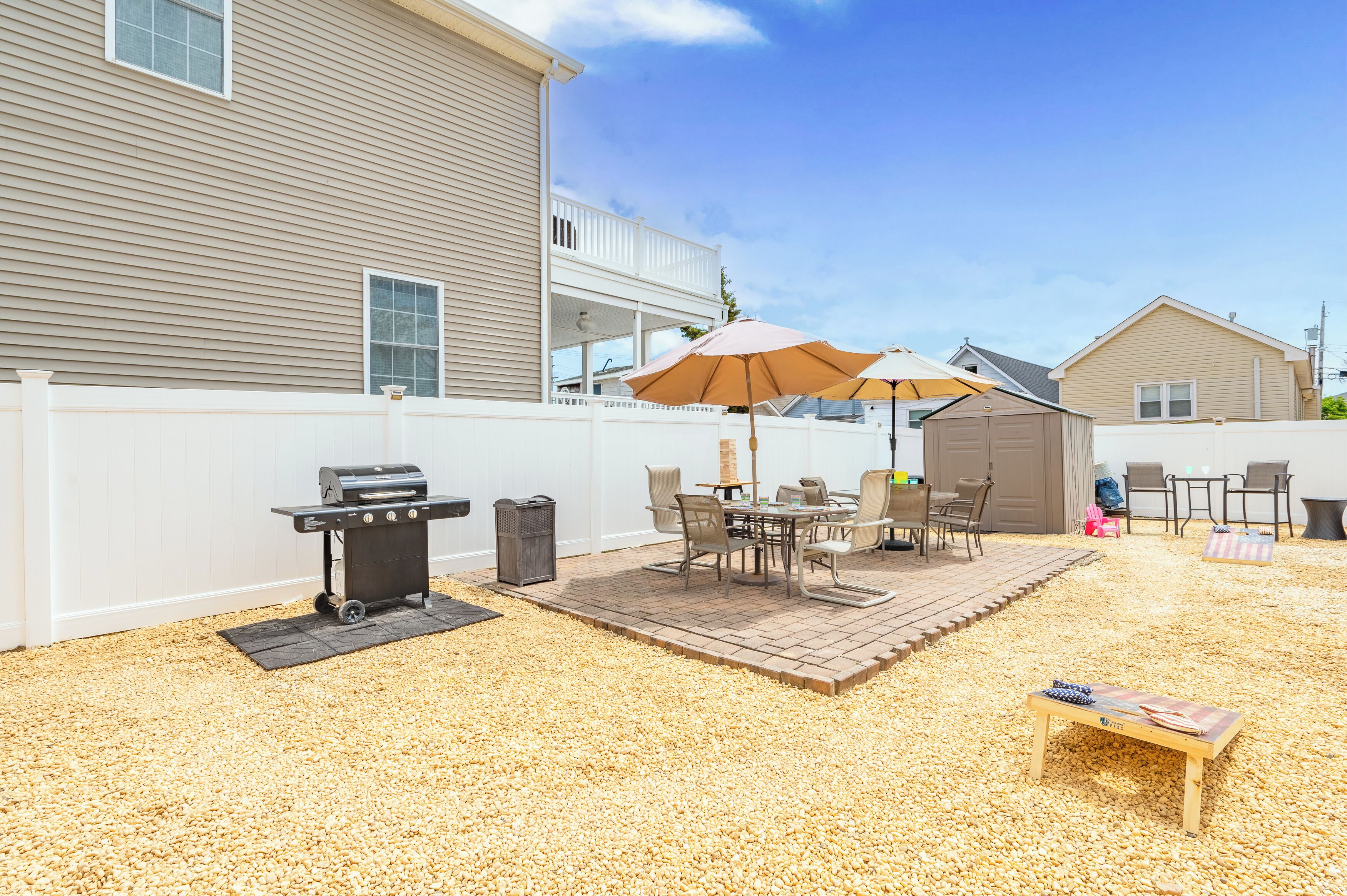 A backyard with a grill, patio furniture, and a covered seating area.