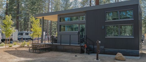 Un bâtiment moderne doté de grandes fenêtres, d’un patio couvert et d’un sol en gravier.