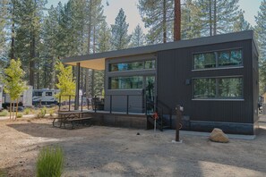 A modern building with large windows, a covered patio, and a gravel ground. - Village Camp Truckee (Truckee)
