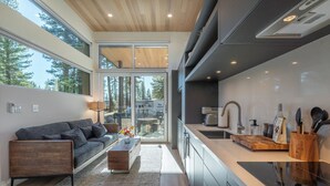 A modern kitchen with a wooden countertop, a sink, and a dining area with a sofa and coffee table. - Village Camp Truckee (Truckee)