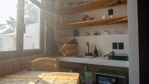 A compact kitchen with wooden shelves, a sink, and a coffee machine.