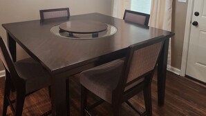 A dining room with a dark wooden table, four chairs, and a chandelier.
