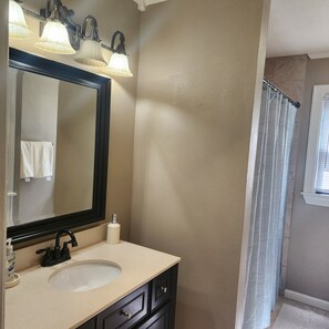 A bathroom with a large mirror, a sink, and a shower curtain.