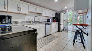 A modern kitchen with white cabinets, a black refrigerator, and a coffee maker.