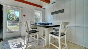 A kitchen with a white table and chairs, a window, and a sign indicating the location.