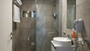 A modern bathroom with a glass-enclosed shower, a sink, and a hairdryer mounted on the wall. - Estudio en Palermo II (Buenos Aires)