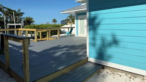 Um deck de madeira com um edifício azul, uma porta e uma cadeira.