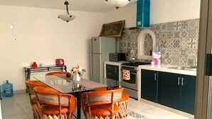 A kitchen with a dining table, chairs, a refrigerator, a microwave, and a stove.