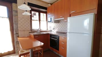 A kitchen with wooden cabinets, a white refrigerator, a stove, and a sink.